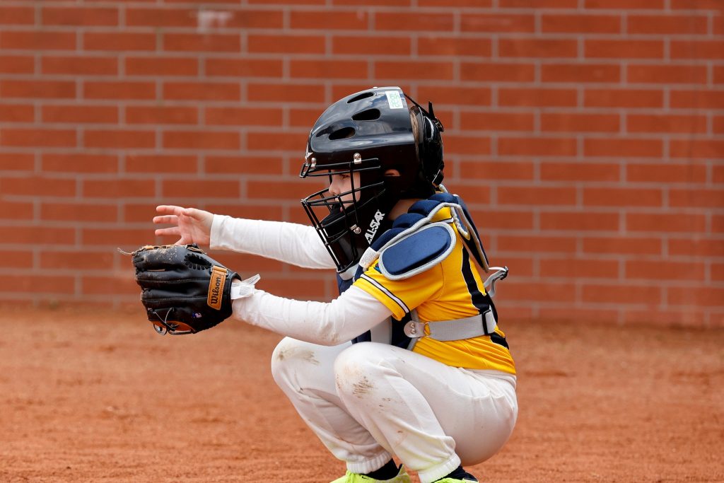 Młody zawodnik chwytający piłkę baseballową podczas zajęć sportowych dla dzieci.